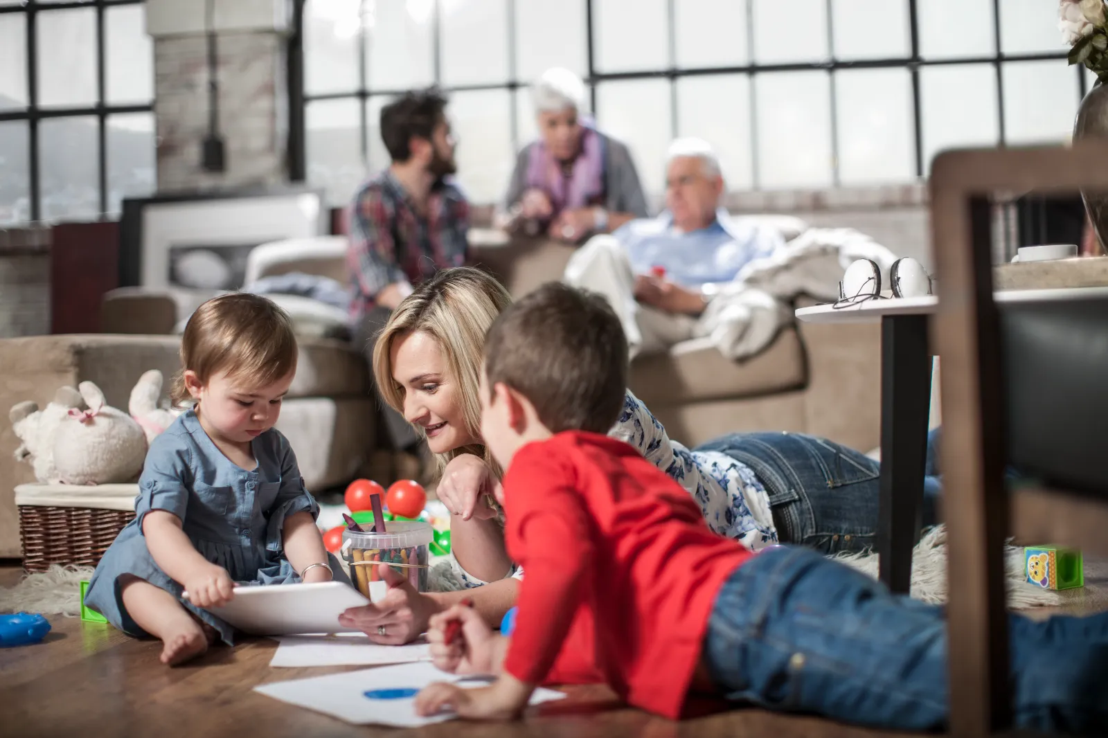 Mother engaging with children drawing at home, showcasing family interaction and child creativity in a cozy living space.